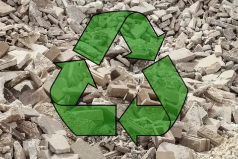 Símbolo de reciclaje verde sobre un montón de escombros de hormigón reciclado.