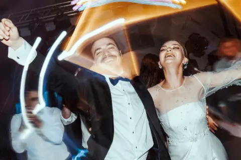 Un couple rayonnant danse joyeusement lors d'un mariage, peut-être celui d'un collègue de travail, sous des lumières festives.