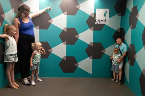 Famille explorant le Paradox Museum Paris, un lieu d'illusions optiques. Avis : une expérience amusante pour tous les âges.