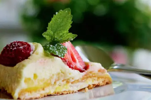 En bit pavlova med lemoncurd, toppad med färska jordgubbar och mynta. En härlig sommardessert.