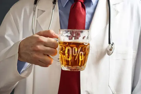 Lekarz w białym kitlu trzyma kufel piwa bezalkoholowego z napisem "0%". Czy piwo bezalkoholowe podnosi ciśnienie?