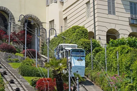 Bergamo kolejka wjeżdża po stromych torach wśród zieleni i zabytkowych budynków.