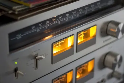 Klasy wzmacniaczy w retro sprzęcie audio. Wskaźniki VU świecą na pomarańczowo, a tuner pokazuje częstotliwość 94 MHz.