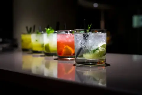 Rząd kolorowych, prostych drinków z wódką, z lodem i miętą, gotowych do podania.