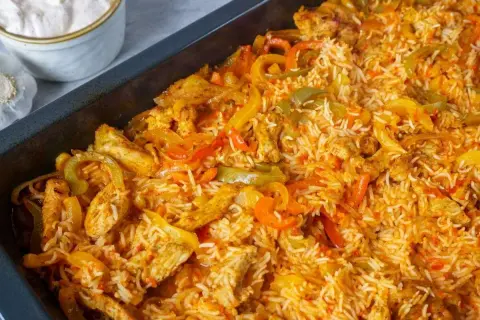 Reis im Backofen mit Hähnchenstreifen und bunten Paprikastreifen. Eine köstliche Mahlzeit, die im Ofen zubereitet wird.