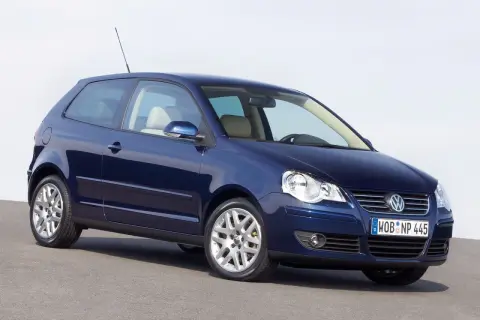 Granatowy Volkswagen Polo 2003, trzydrzwiowy, z jasnym wnętrzem, stoi na szarej nawierzchni.
