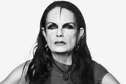 Black and white portrait of Michèle Lamy with dramatic eye makeup and a line drawn on her forehead.