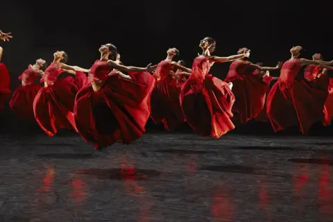 Danzarinas con vestidos rojos vibrantes en el escenario, evocando la fuerza de Carmina Burana en Zaragoza.