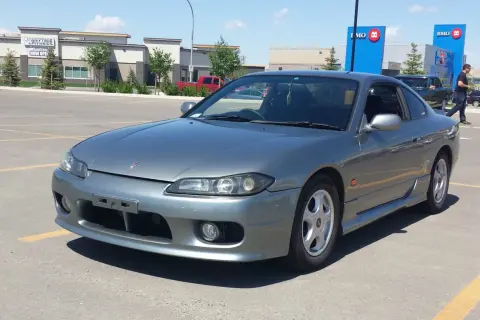 Szary Nissan Silvia s15 na parkingu przed budynkami BMO i Anytime Fitness.