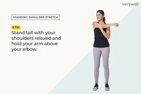 Woman performing standing shoulder stretches, holding one arm across her chest.
