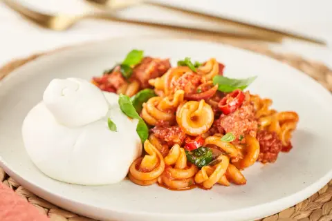 Pasta mit Salsiccia-Sauce und Burrata auf einem Teller.