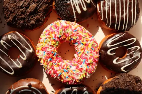 Kolorowe pączki z posypką i czekoladowe z polewą, idealne na cheat day.