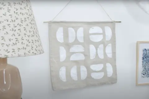 Idée tableau peinture à faire soi-même : tissu beige orné de formes géométriques blanches, style moderne et épuré.