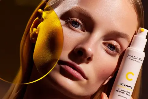 Strahlende Haut dank Vitamin C Skin Care. Eine Frau hält eine Flasche MÁDARA Illuminating Recovery Cream.