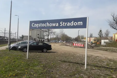 Tablica z napisem Częstochowa Stradom. W tle budynki, tory kolejowe i samochody.