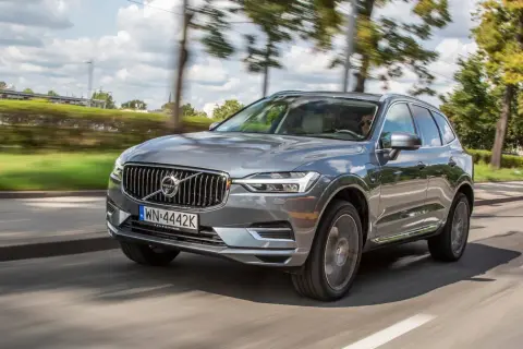 Szary Volvo XC60 T8 w ruchu, z rozmytym tłem drzew i nieba.
