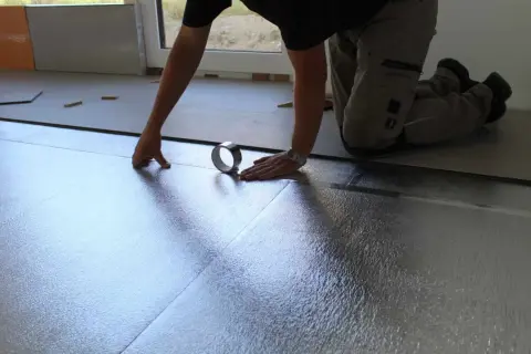 Instalando la mejor base aislante para suelo laminado. Se coloca una lámina plateada reflectante, asegurando un aislamiento térmico y acústico óptimo.