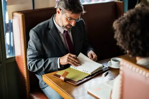 Biznesmen w garniturze przegląda notatki, planując swoje finanse. Może szukać informacji o **novum pozyczki online**.