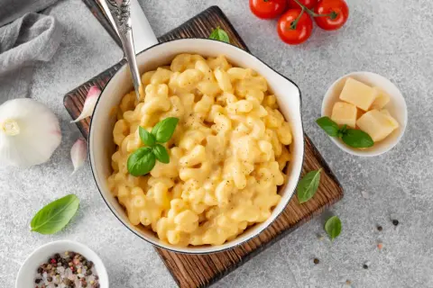 Pyszne, kremowe mac and cheese w białej misce, z bazylią i pomidorkami koktajlowymi. Idealne, gdy zastanawiasz się, jak podgrzać mac and cheese.
