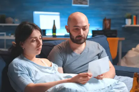 Zmartwieni rodzice czytają list. Martwią się, czy komornik może zająć rentę rodzinną na dziecko.