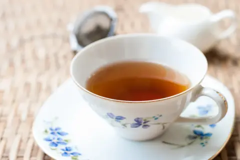 Aromaticzna herbata earl grey, znana ze swoich właściwości pobudzających i relaksujących, w eleganckiej filiżance z niebieskimi kwiatami.
