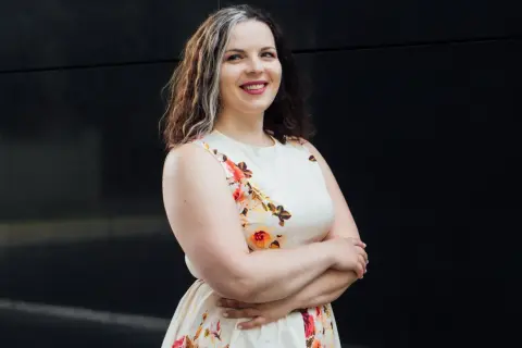Uśmiechnięta kobieta w kwiecistej sukience, szukająca tanich sukienek plus size na wesele.