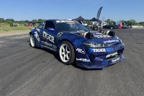 Niebieski samochód driftowy s15 z podwójnymi turbosprężarkami i licznymi sponsorami, gotowy do akcji.
