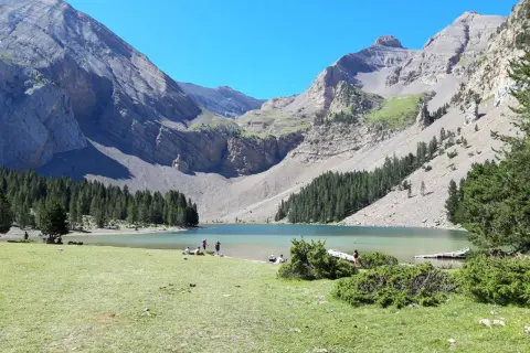 Ibón de Plan con montañas, bosque y gente en la orilla.