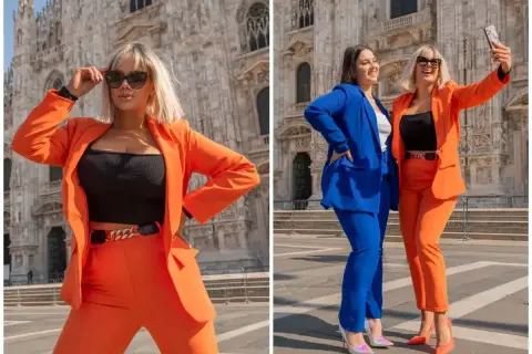 Dwie kobiety w modnych, pomarańczowych stylizacjach pozują na tle katedry. Jedna z nich robi selfie.