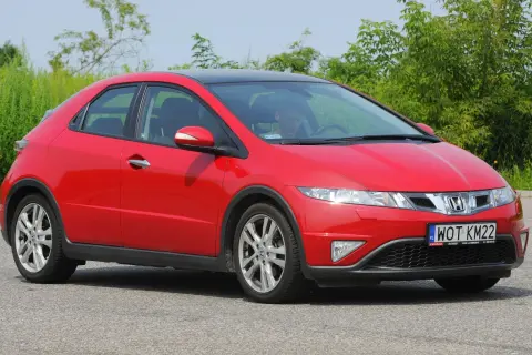 Czerwony Honda Civic 8 z czarnym dachem, zaparkowany na drodze. Widać przednie światła i grill.