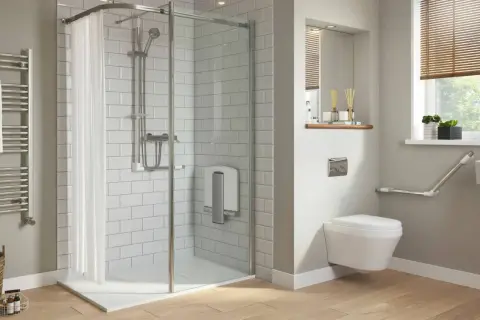 Salle de bain moderne avec douche de sol, carrelage blanc, porte-serviettes chauffant et WC suspendu avec barres d'appui.