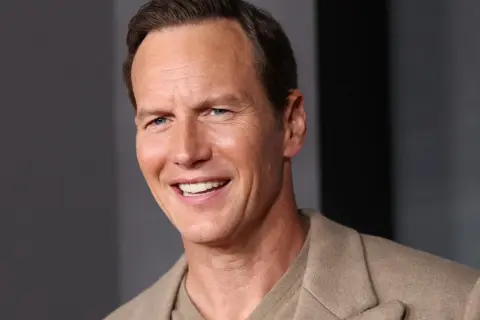 Uśmiechnięty Patrick Wilson, znany z wielu filmów, w beżowej marynarce.