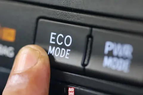Palec naciska przycisk "ECO MODE", pytając "econ co to?". Obok przycisk "PWR MODE".