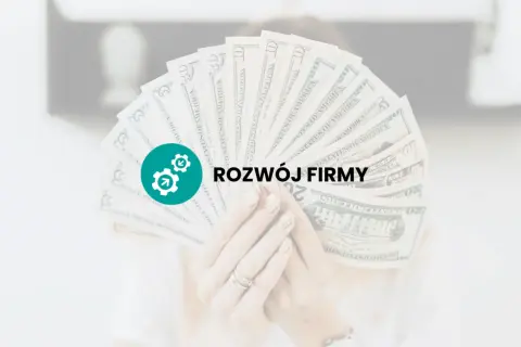 Dłoń trzyma wachlarz banknotów dolarowych z ikoną i napisem "ROZWÓJ FIRMY".