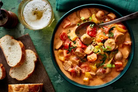Herzhaftes Wurstgulasch mit Paprika und Tomaten, serviert mit frischem Brot und einem kühlen Bier. Ein tolles Rezept für gemütliche Abende.