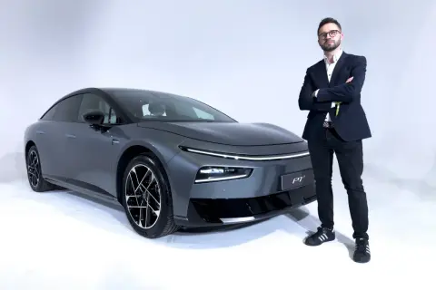 Elegancki mężczyzna w garniturze stoi obok szarego XPeng P7.