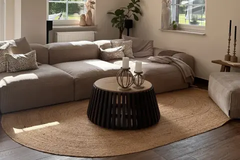 Alfombra redonda de yute, uno de los tipos de alfombras más naturales y versátiles, complementa un salón moderno con sofá modular y mesa de centro.