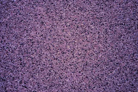 Fioletowy tynk mozaikowy o drobnej ziarnistości. Wydajność 25 kg na ok. 3-4 m², zależnie od grubości warstwy.