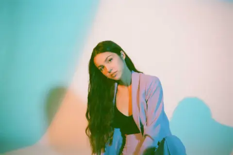 Olivia Rodrigo w pastelowej marynarce, z długimi włosami, jakby pozowała do okładki jednego ze swoich albumów.