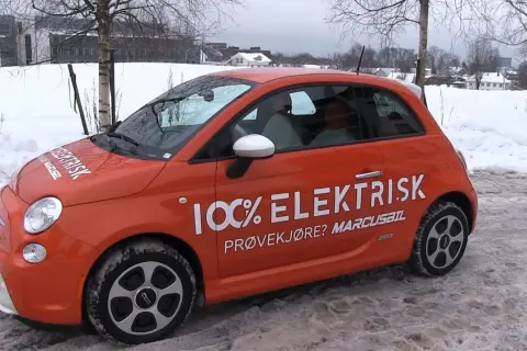 Pomarańczowy Fiat 500e w zimowej scenerii, z napisem "100% ELEKTRISK". Sprawdź zasięg tego elektryka!