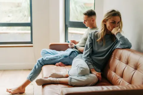 Een vrouw denkt diep na, terwijl een man op zijn telefoon kijkt. Het lijkt erop dat opposites attract betekenis hier niet opgaat.
