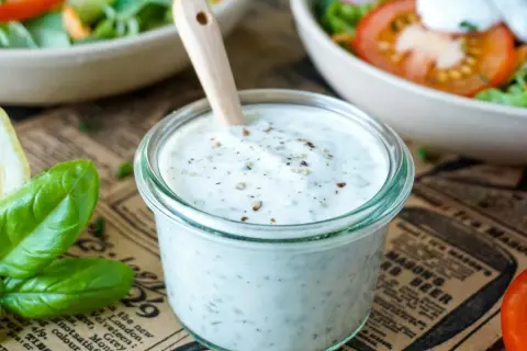 Cremiges Joghurt Dressing mit Kräutern in einem Glas, bereit für einen frischen Salat.