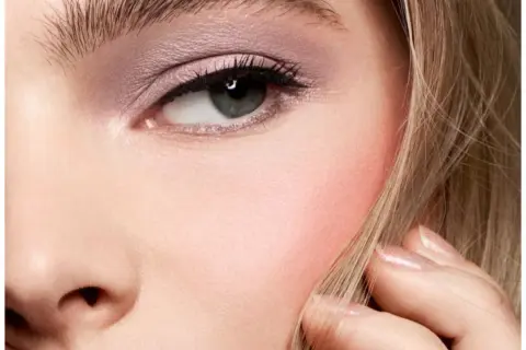 Un occhio truccato con ombretto rosa e un tocco di blush sulle guance, che dona un aspetto sano e radioso.