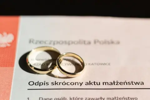Złote obrączki na odpisie skróconym aktu małżeństwa, symbolizujące związek.