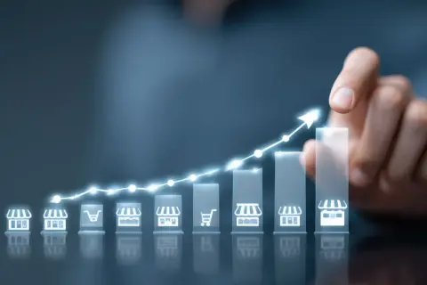 Wykres wzrostu z ikonami sklepów i koszyka, symbolizujący strategię cross selling i rozwój biznesu.