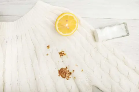 Maglione bianco con macchia di ruggine. Limone e sale pronti per rimuoverla.
