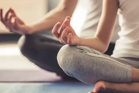 Zwei Personen in entspannter Haltung, Hände in Mudras. Eine friedliche Szene, die Entspannungstechniken bei Stress zeigt.