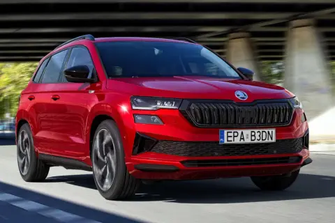 Czerwona Skoda Karoq w ruchu, z widocznym grillem i światłami. Poznaj jej wymiary i możliwości.