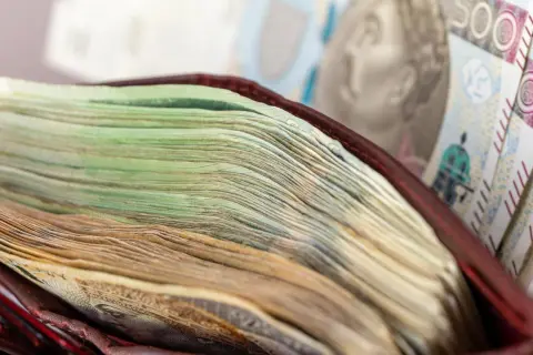 Stos banknotów w portfelu, w tle banknot 500 zł.