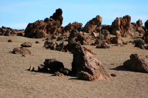 Paisaje desértico con rocas volcánicas rojizas y arena, evocando la zona de las minas de San José.
